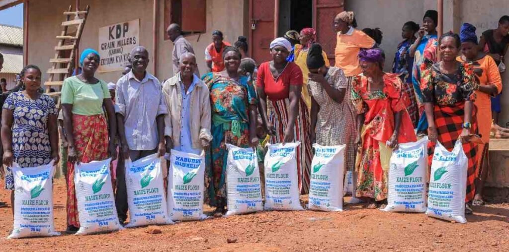 An elderly community member receiving a sack of maize flour from staff at Kabubbu’s maize mill.