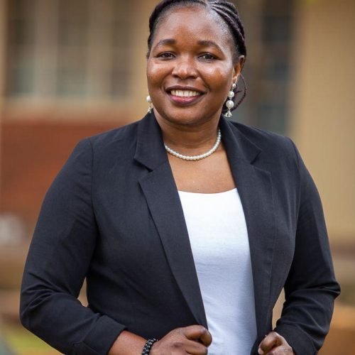 Deputy Director of Kabubbu Development Project Portrait of the Deputy Director of Kabubbu Development Project standing outside in a black blazer and white top, smiling confidently.